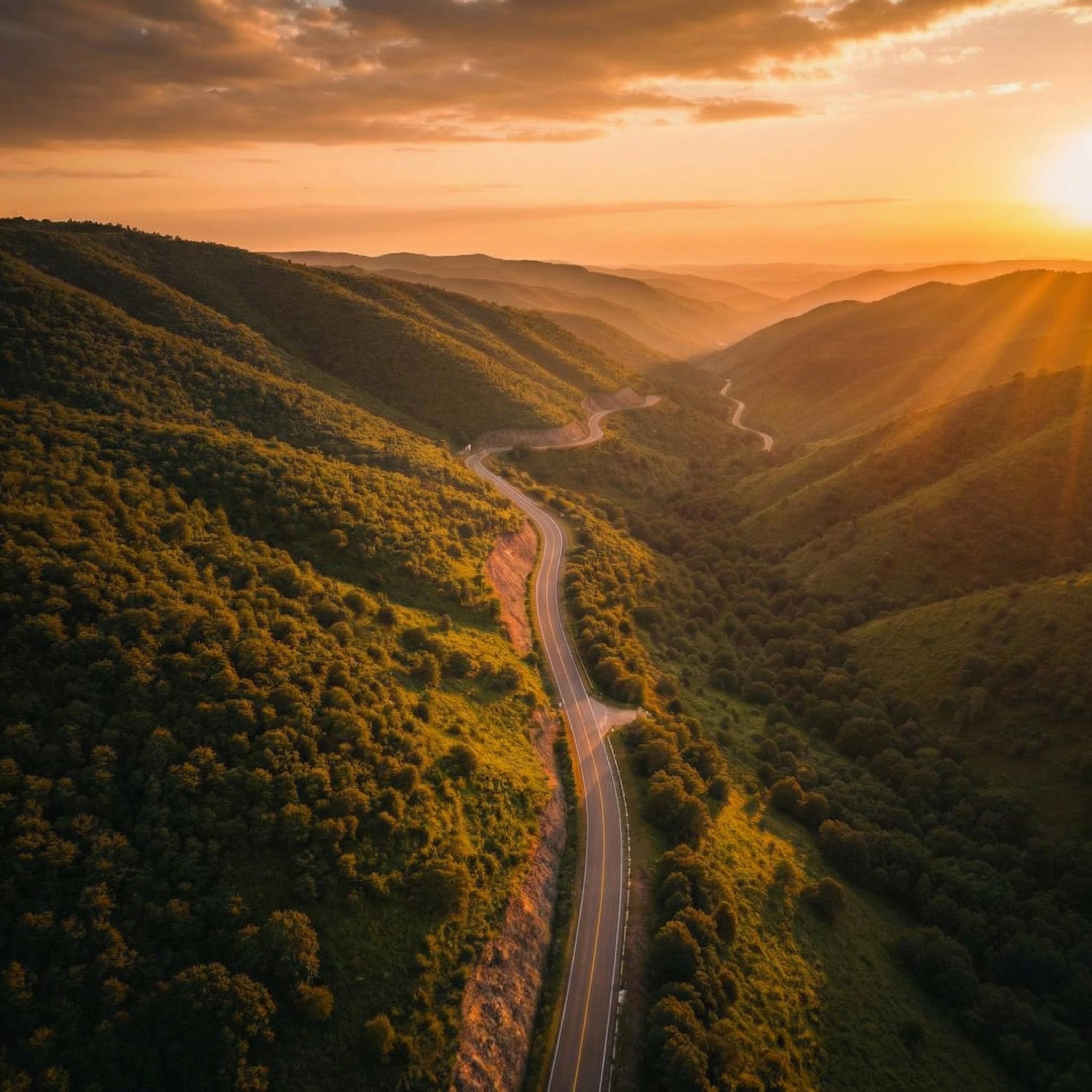 Winding mountain road through lush green valleys at sunset